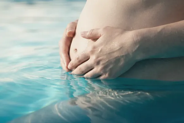 Acquagravidanza — il pancione di una futura mamma sostenuto dall'acqua calda di una vasca Ondarte