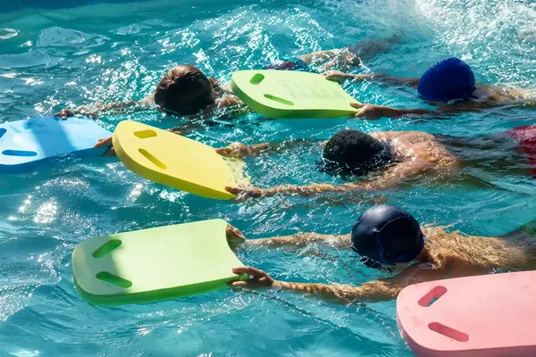 Un gruppo di bambini avanza con le tavolette galleggianti durante una lezione di nuoto Ondarte — Nuoto bambini e ragazzi